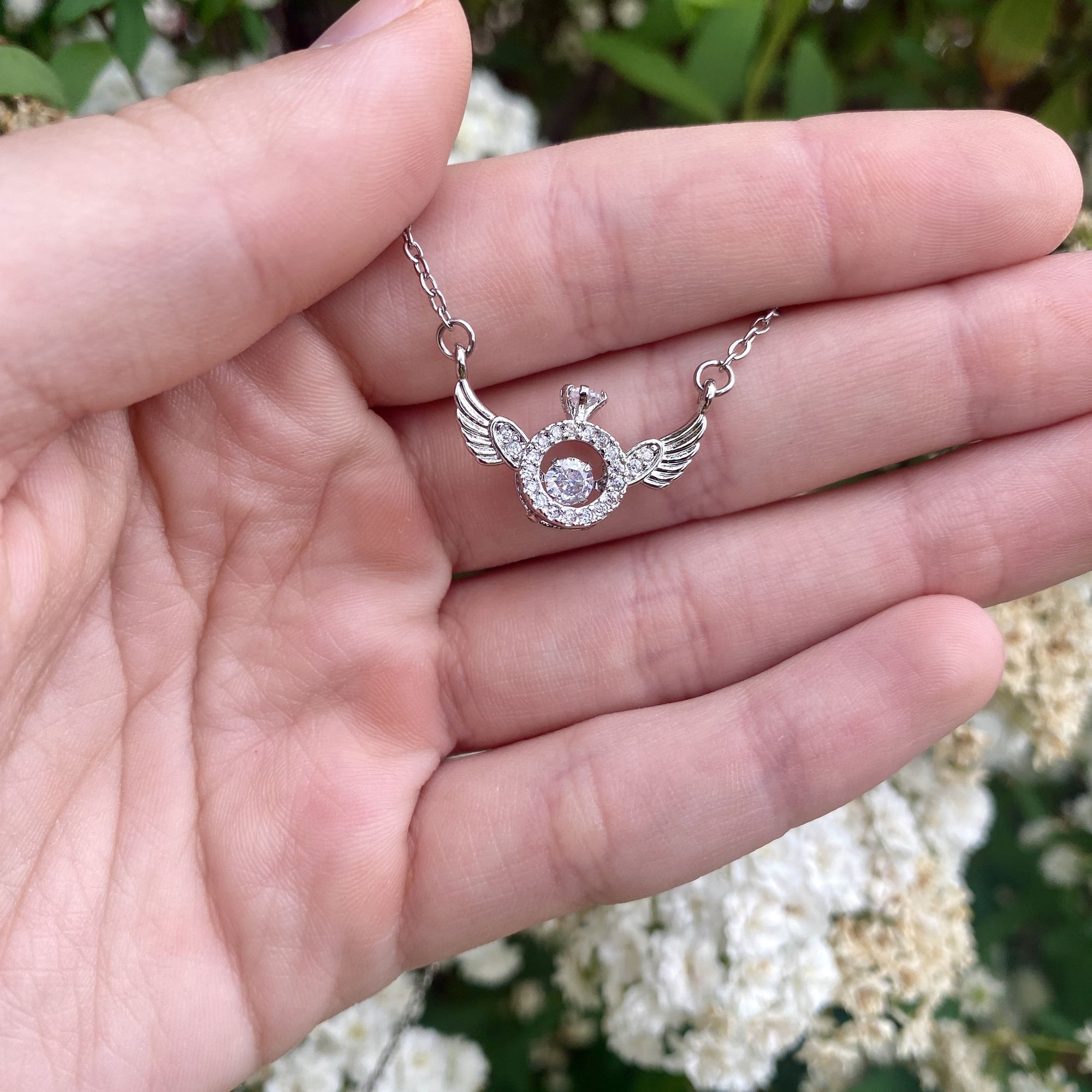 An angel wing necklace held out in an open palm