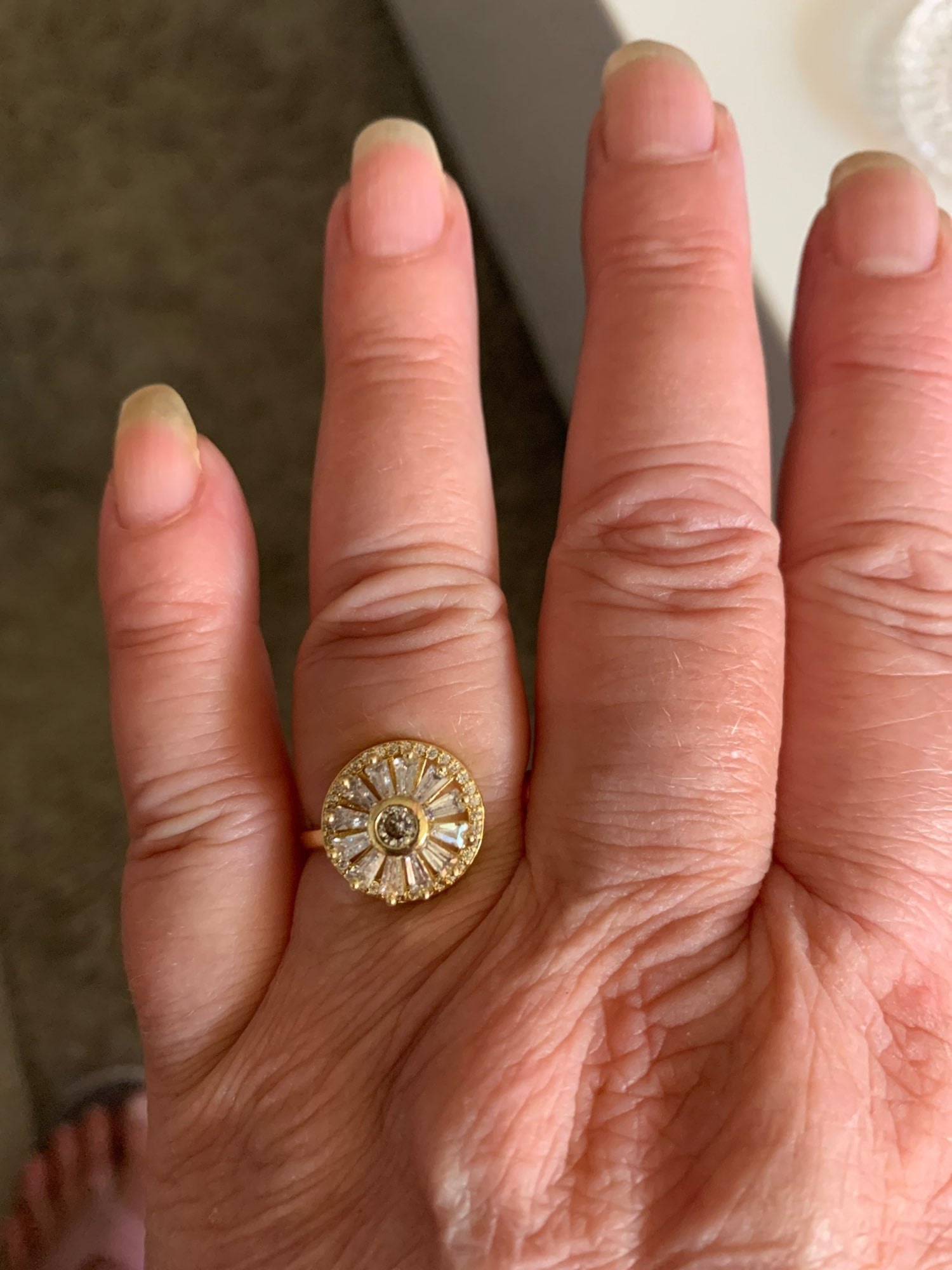 The sunburst spinner ring in gold on a hand