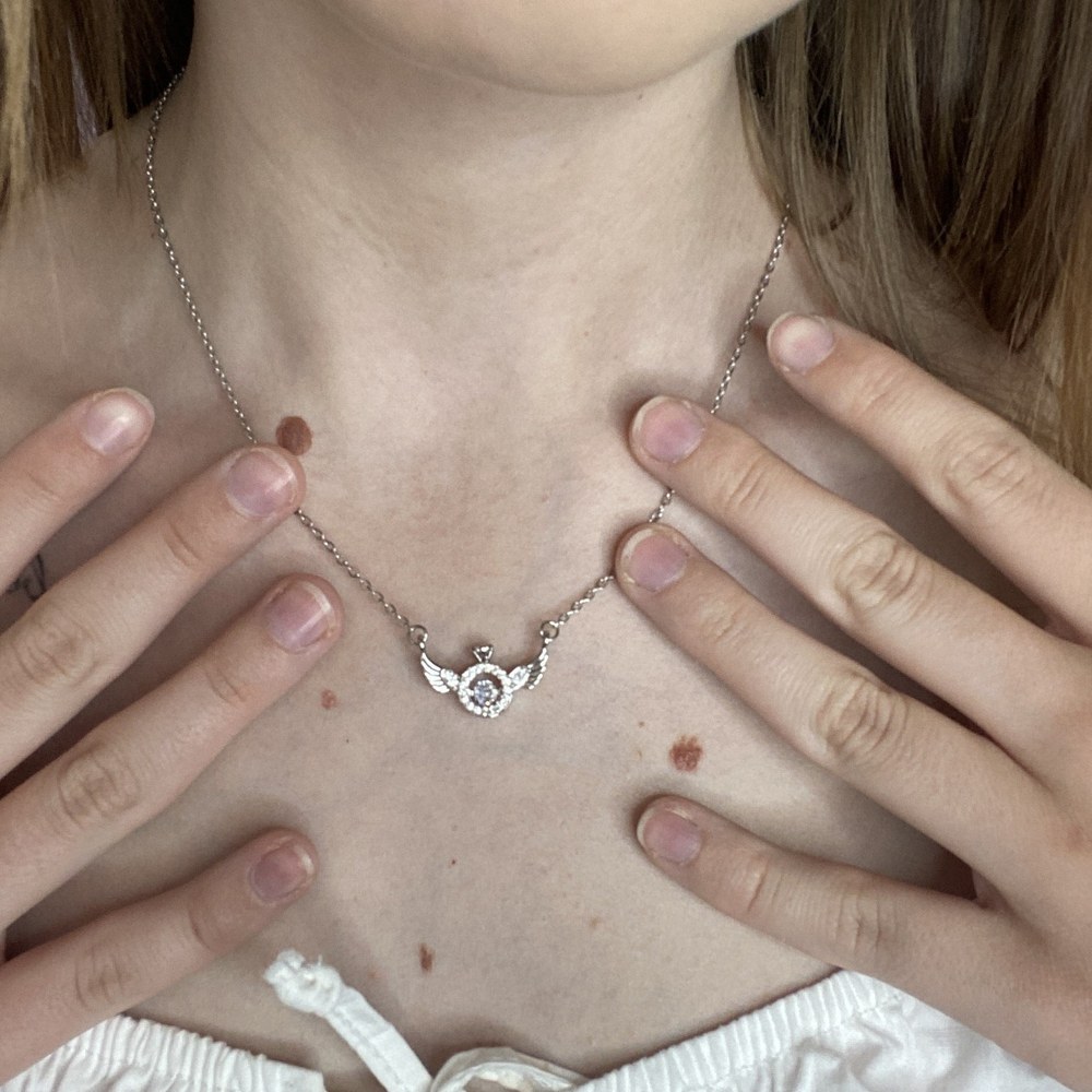 The angel wing necklace worn at the collarbone